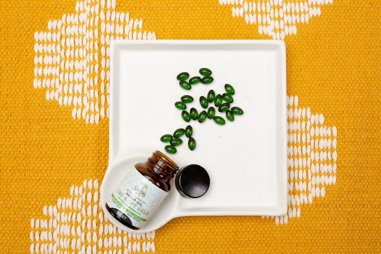 services-04 CBD oil capsules in a bottle on a white tray over an orange patterned fabric. Ideal for health and wellness themes.