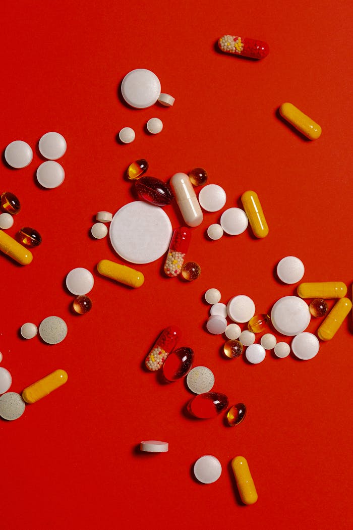 services-bg A diverse array of pills and capsules scattered on a vibrant red surface.
